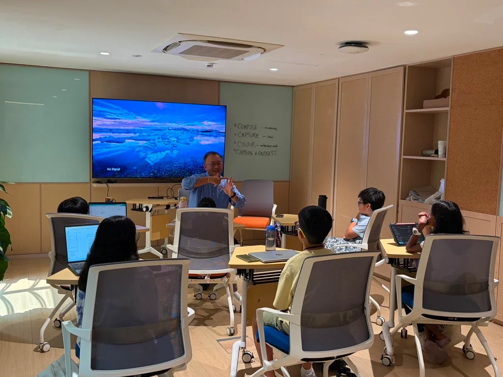 A group discussion with children seated around classroom tables