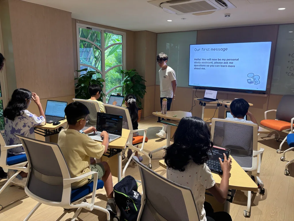Children try study-assistant prompts on laptops and tablets with an instructor nearby